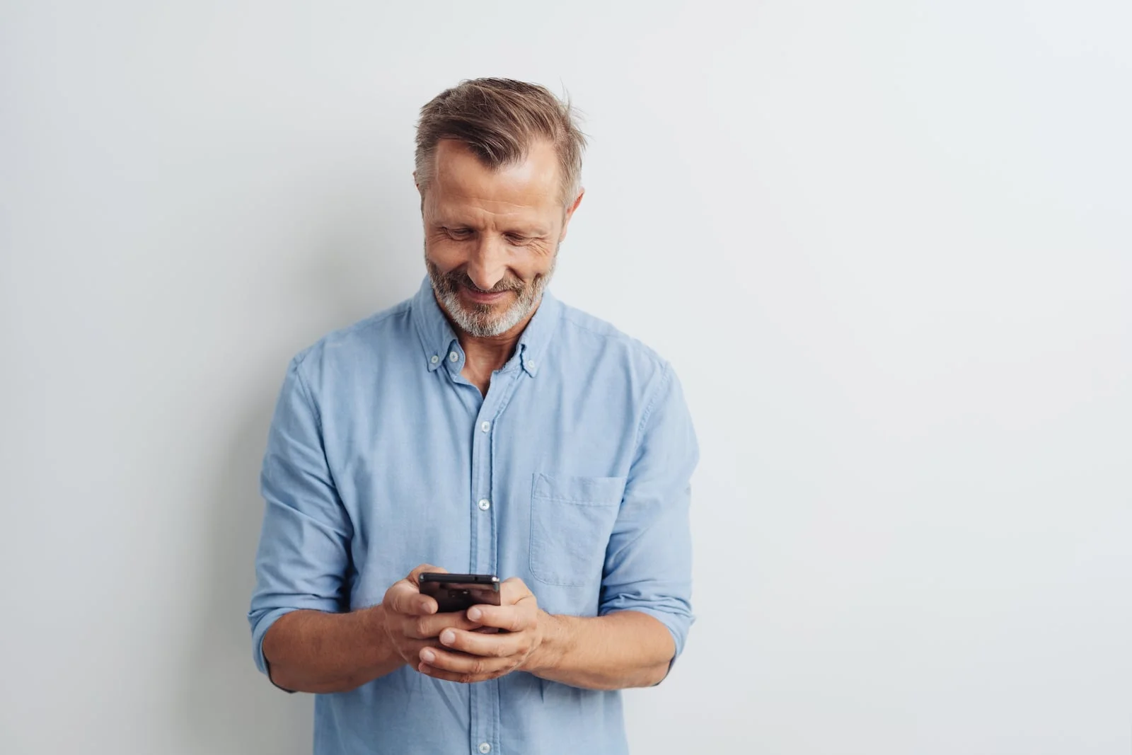 man_looking_at_phone man looking down at his phone smiling